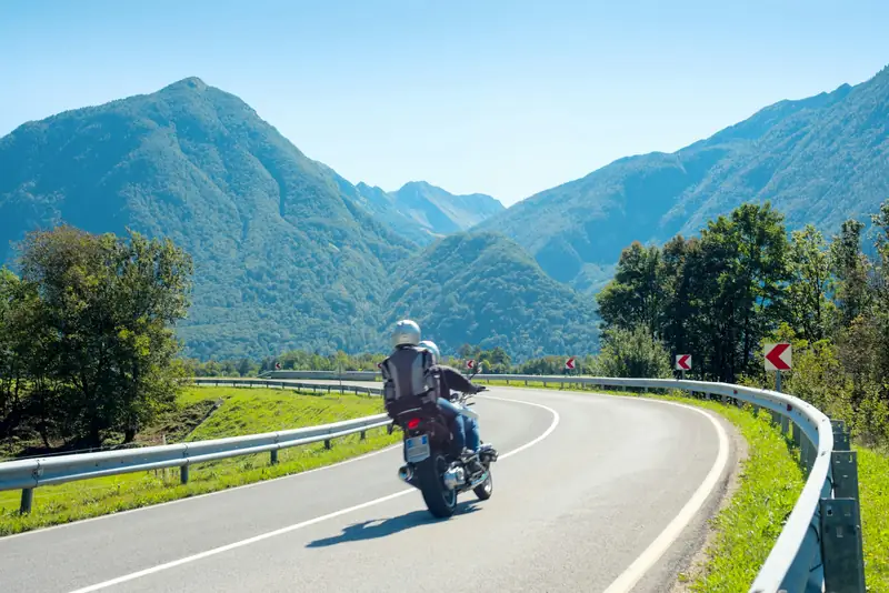Motorista tomando una curva en una carretera de montaña un día soleado